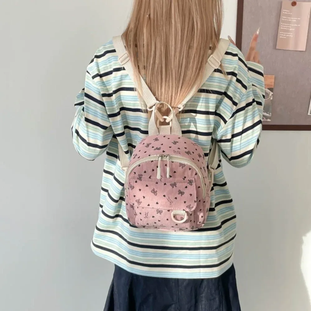 Mini sac à dos en velours côtelé avec imprimé cœur et nœud, sac à bandoulière multi-compartiments, ouverture zippée, sac à dos décontracté léger pour l'école