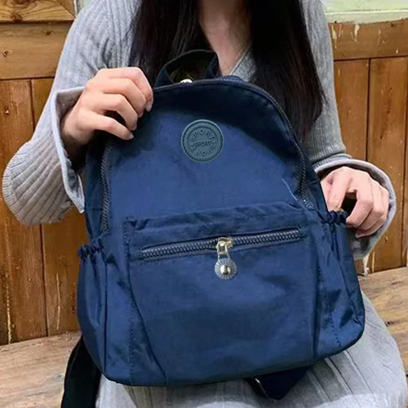 sac à dos de style neutre pour hommes et femmes, adapté aux voyages et à la photographie en nylon, avec un logo rond.