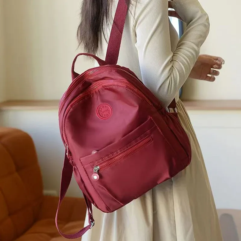 sac à dos de style neutre pour hommes et femmes, adapté aux voyages et à la photographie en nylon, avec un logo rond.