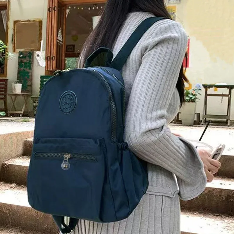 sac à dos de style neutre pour hommes et femmes, adapté aux voyages et à la photographie en nylon, avec un logo rond.